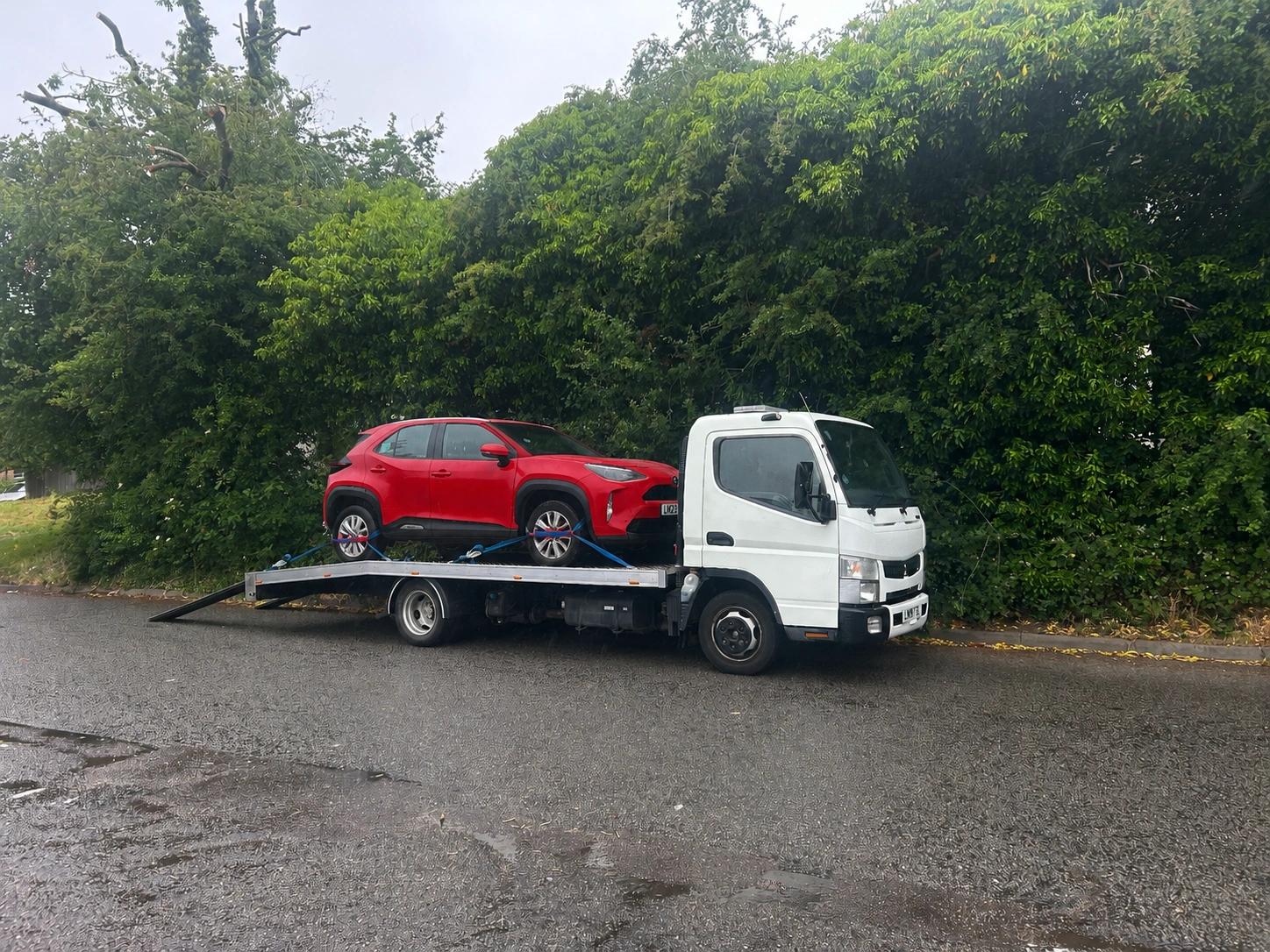 Hard shoulder recovery truck carrying car on motorway